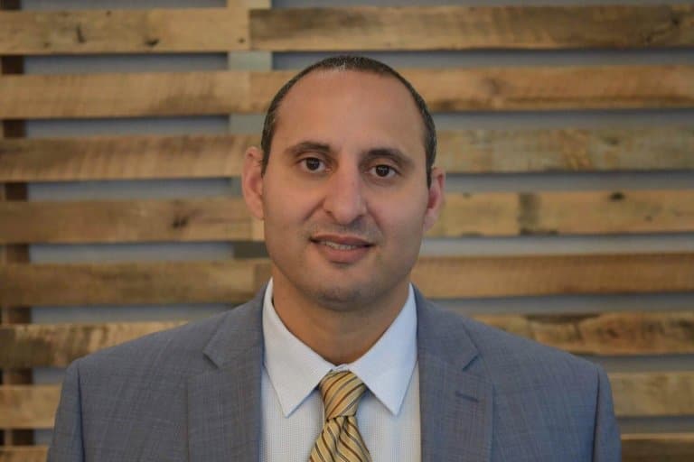 a man wearing a suit and tie smiling at the camera